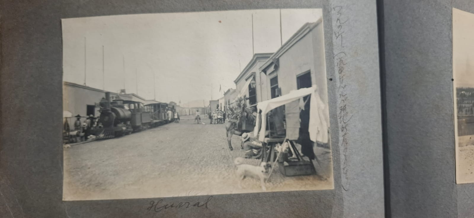 Fotografía histórica de un ferrocarril en Huancayo, Perú, junto a edificios y personas, conservada en un álbum de época con anotaciones manuscritas en japonés.